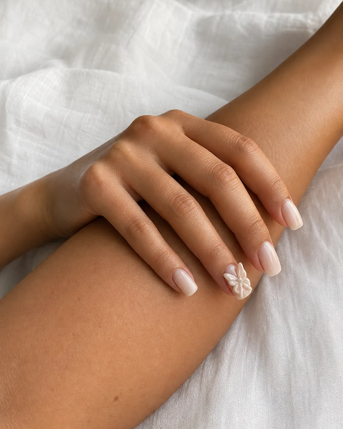 Close-up of medium square nails with a milky nude base and a sculpted 3D butterfly with slightly lifted wings, on medium skin resting on opposite forearm