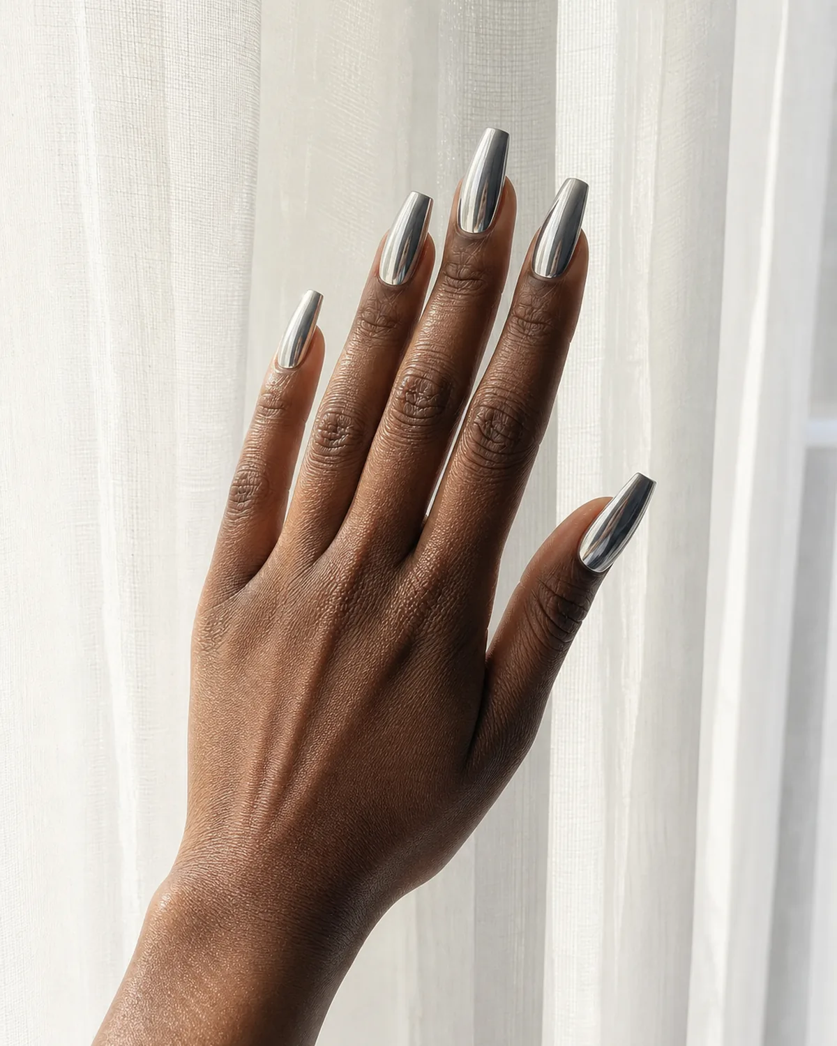 Medium coffin acrylic nails in mirror chrome silver finish catching window light