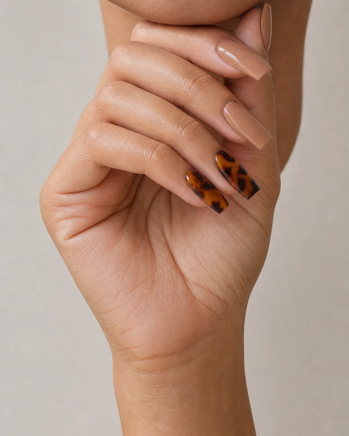 Medium coffin acrylic nails with tortoiseshell print on ring and middle finger over nude base