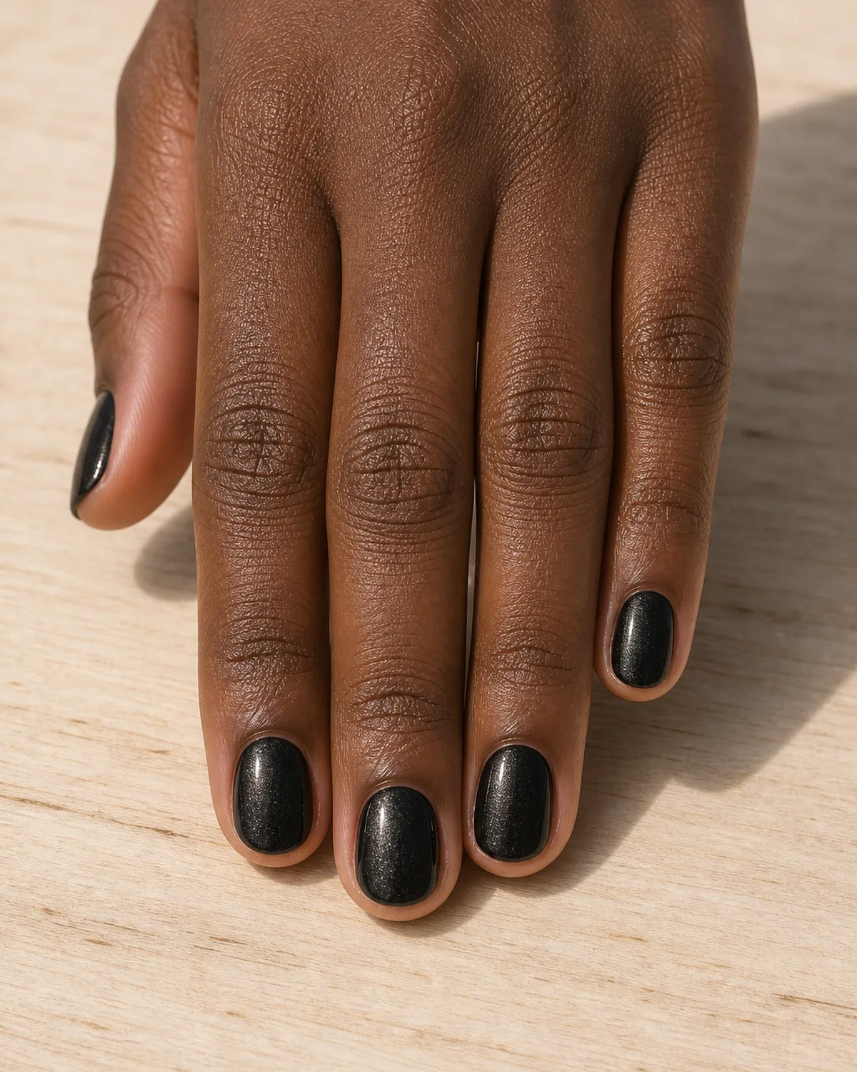 Black cream with soft satin shimmer on short round nails
