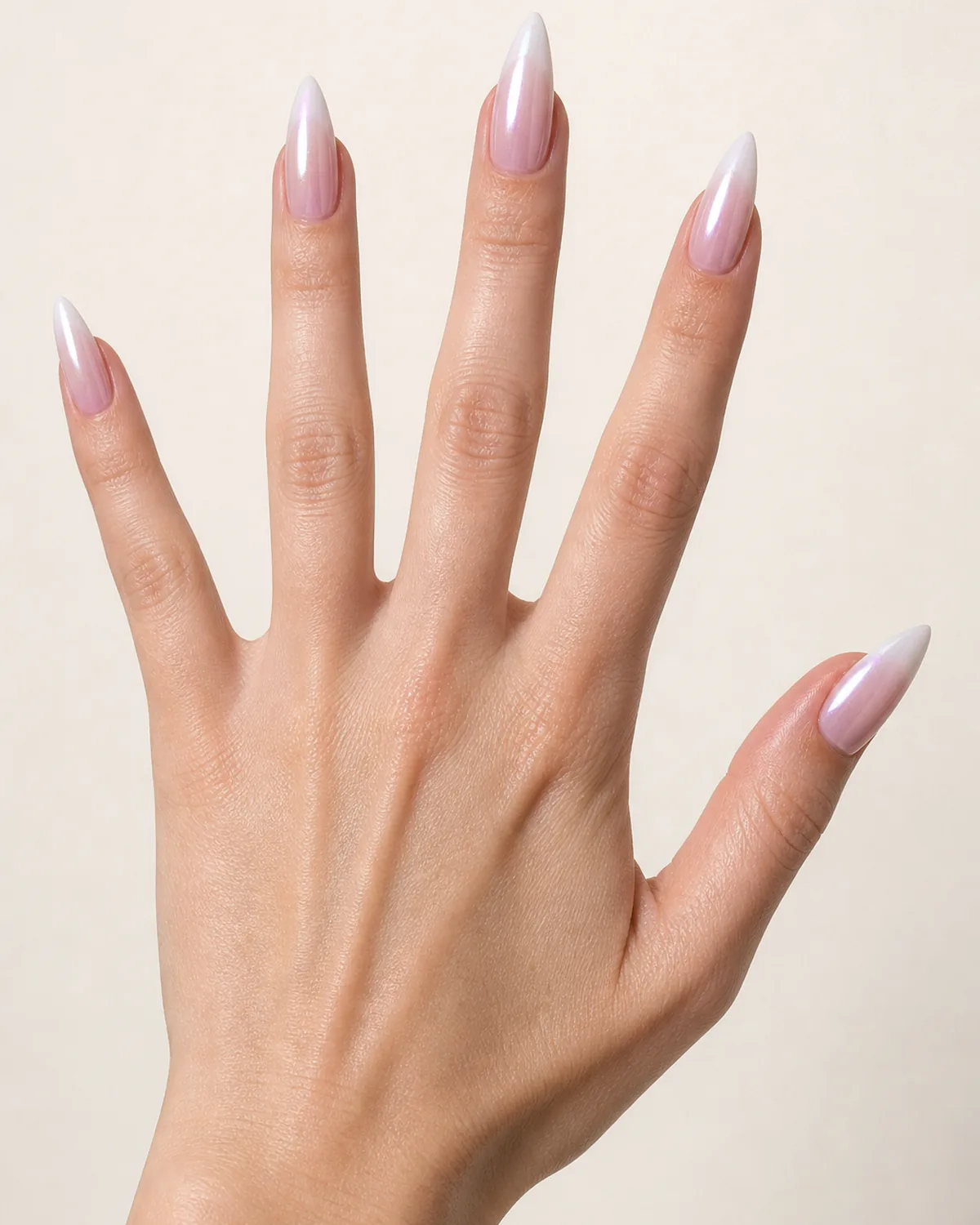 Fingers fanned against a pale backdrop, medium stiletto nails with pearl chrome French ombre, light neutral skin