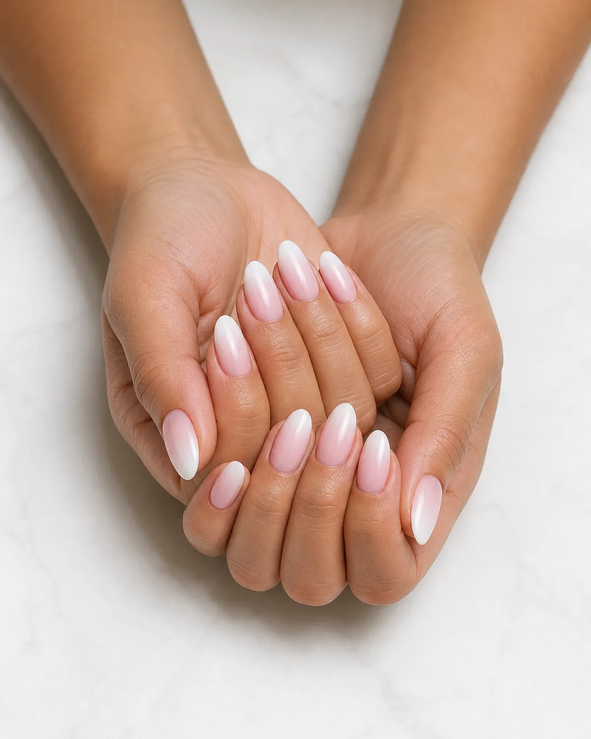 Two hands cupped with loosely interlaced fingers, medium oval nails with deep-coverage French ombre gradient