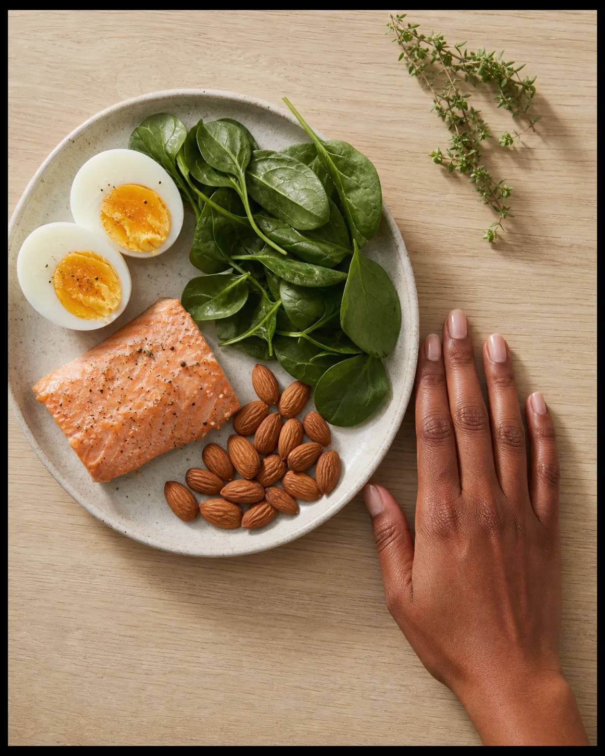 Overhead flat-lay of biotin-rich foods on a cutting board with a hand showing healthy natural nails at the edge