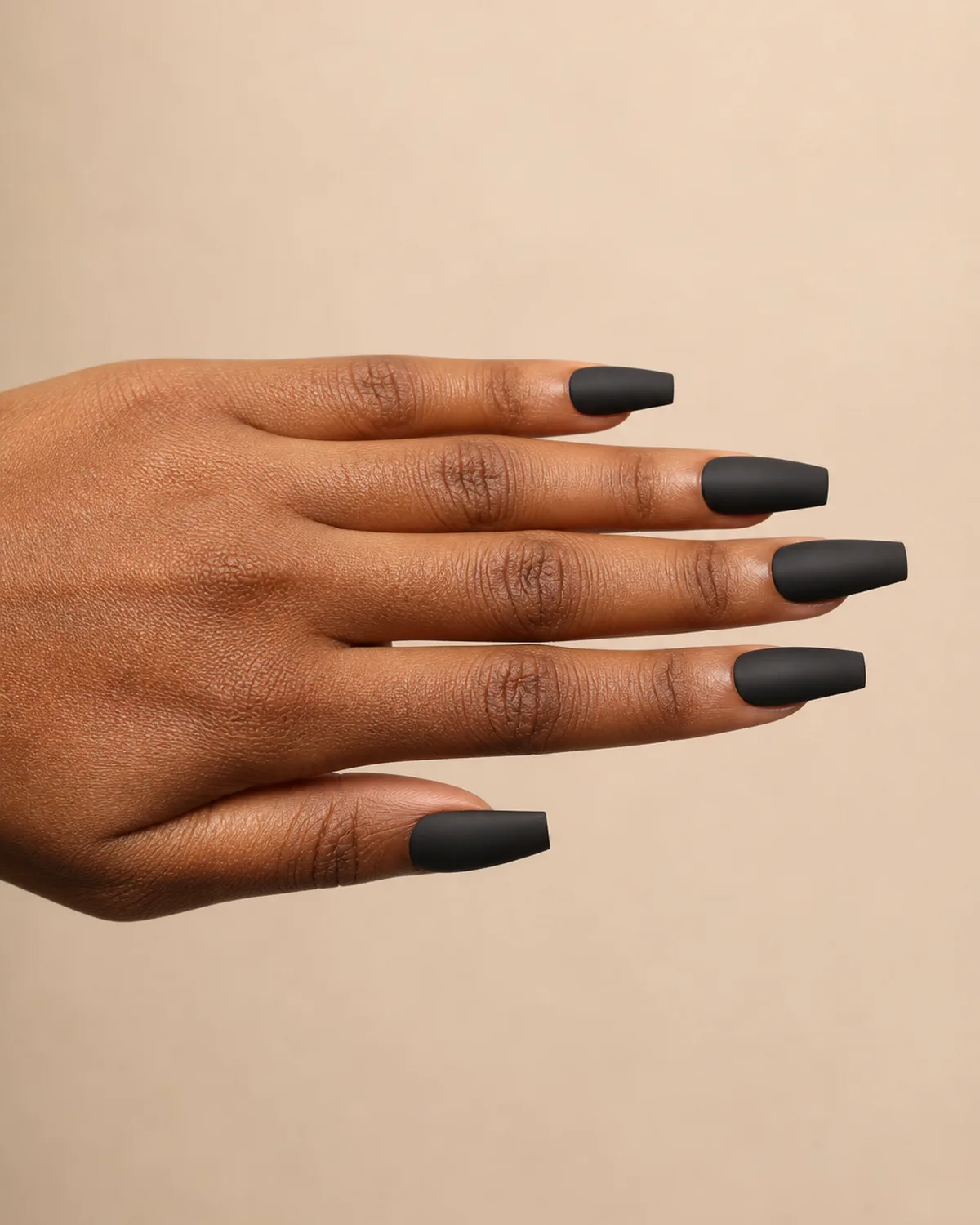 Side profile of one hand with matte black coffin-shaped press-on nails, fingers extended horizontally showing sharp filed edges and flat tip