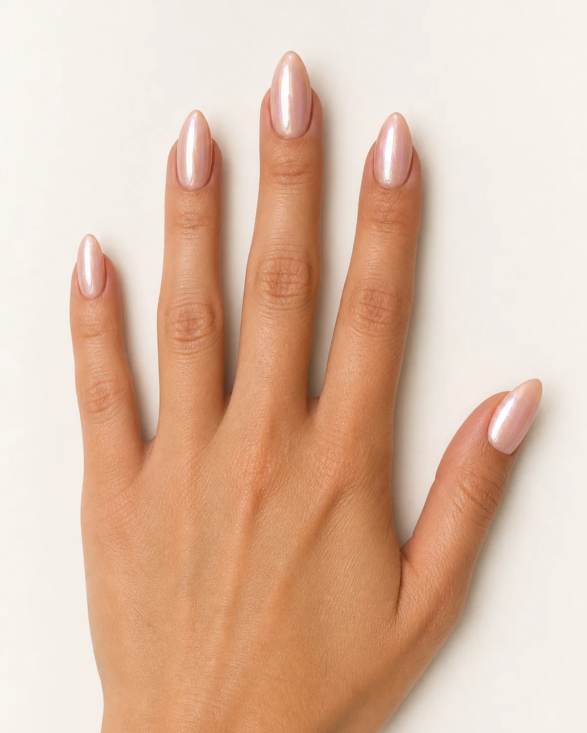 Overhead view of a single hand splayed flat with glazed donut finish press-on nails on almond shape, iridescent shimmer catching soft studio light