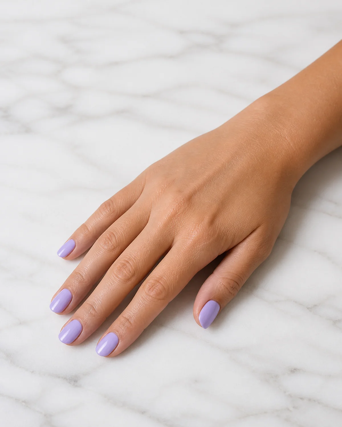 Single right hand with opaque soft lavender nails on short almond shape palm down on white marble surface