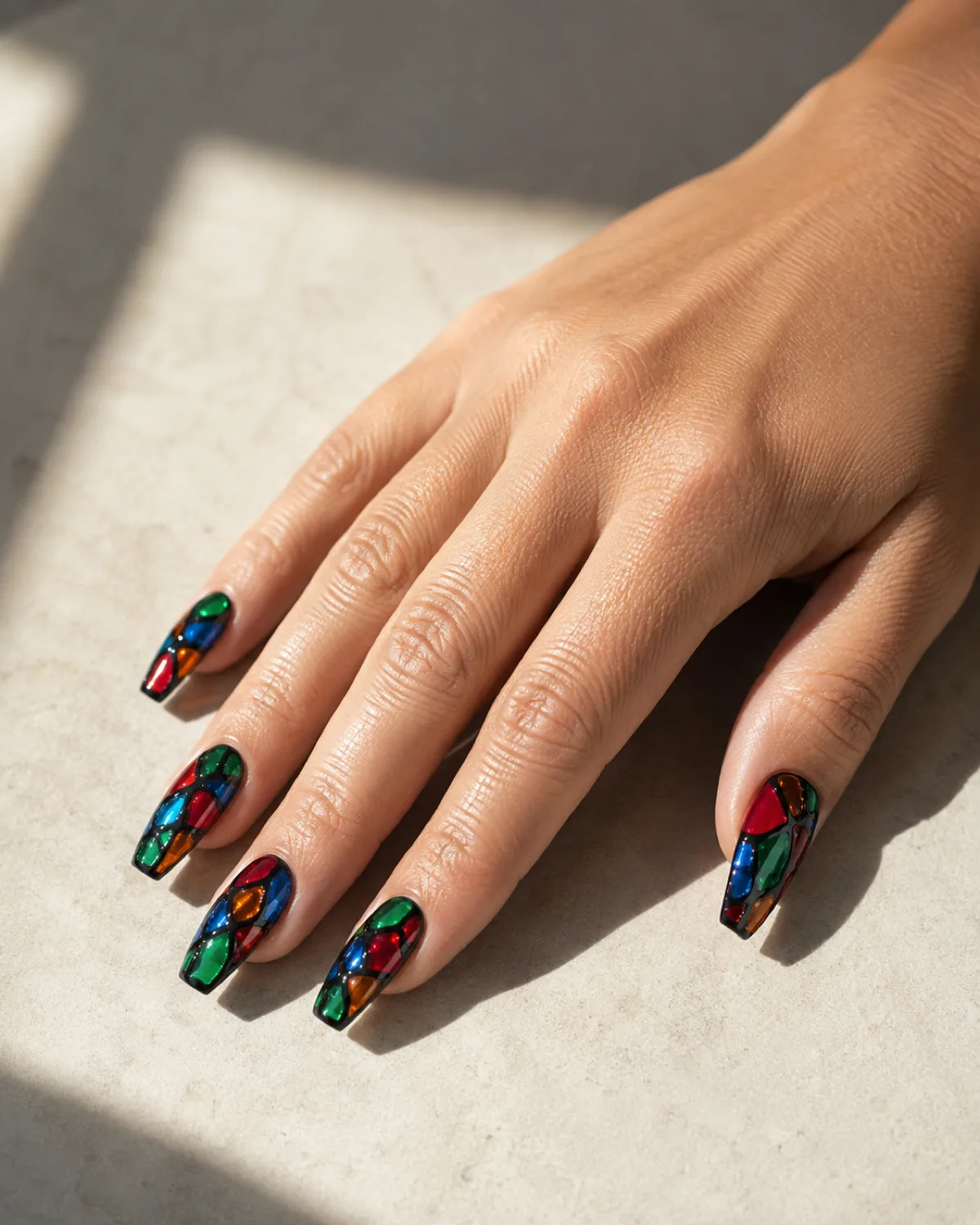 Single right hand with medium coffin nails in jewel-tone stained glass abstract panels of emerald sapphire ruby and amber with black outlines