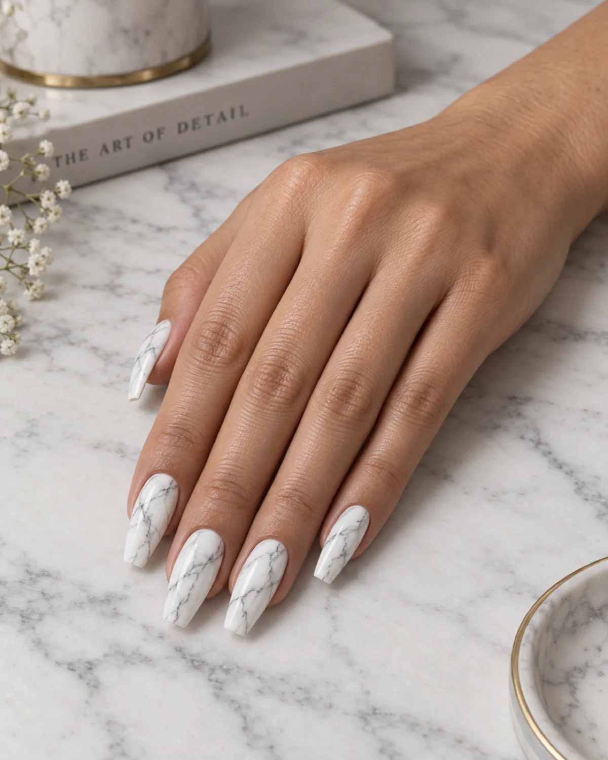Single right hand with white base and fine gray marble veining on ballerina nails resting on a white marble board