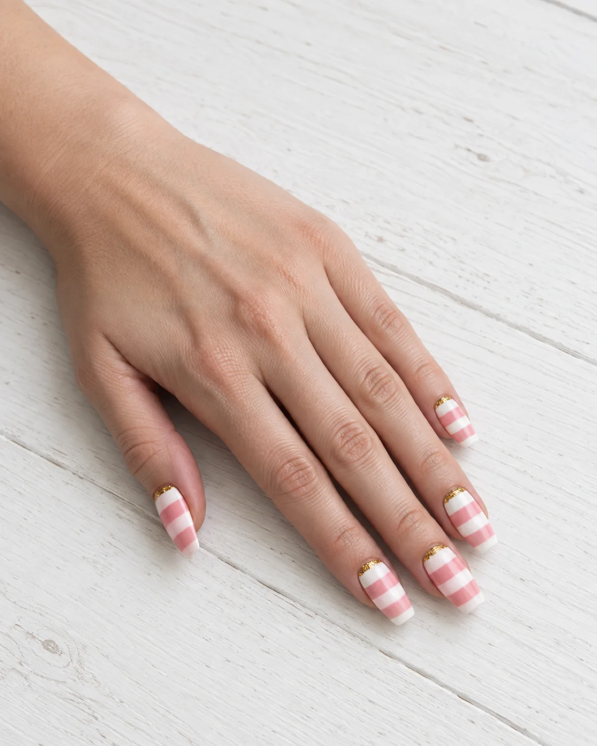 Single left hand with birthday cake layered nails on medium coffin shape resting on white wood