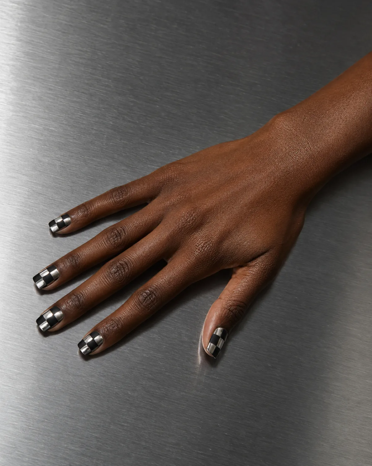 Single right hand with chrome silver mirror squares and matte black squares on square nails on brushed aluminium