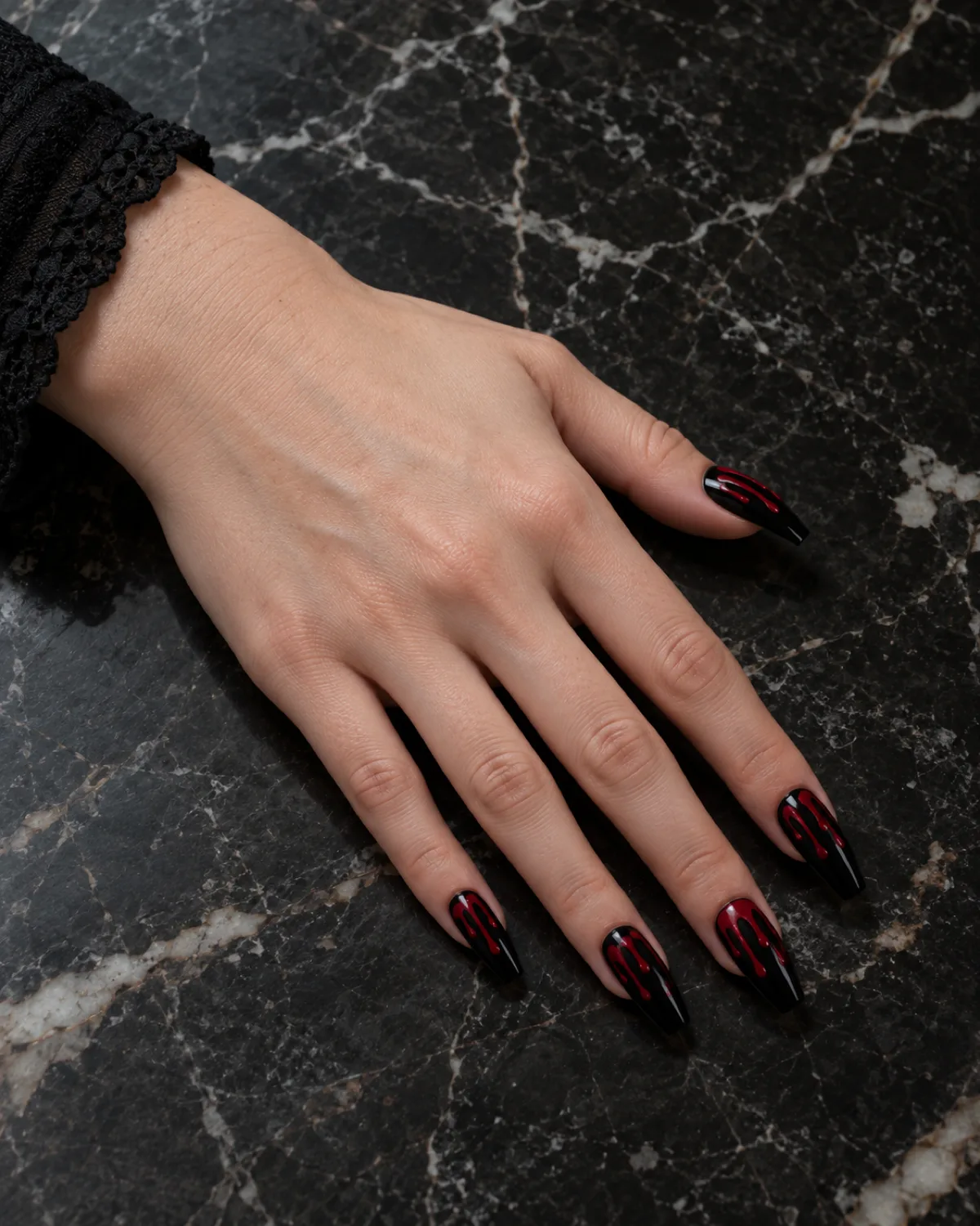 Black coffin nails with deep crimson drip lines bleeding from cuticle toward tips on dark marble surface