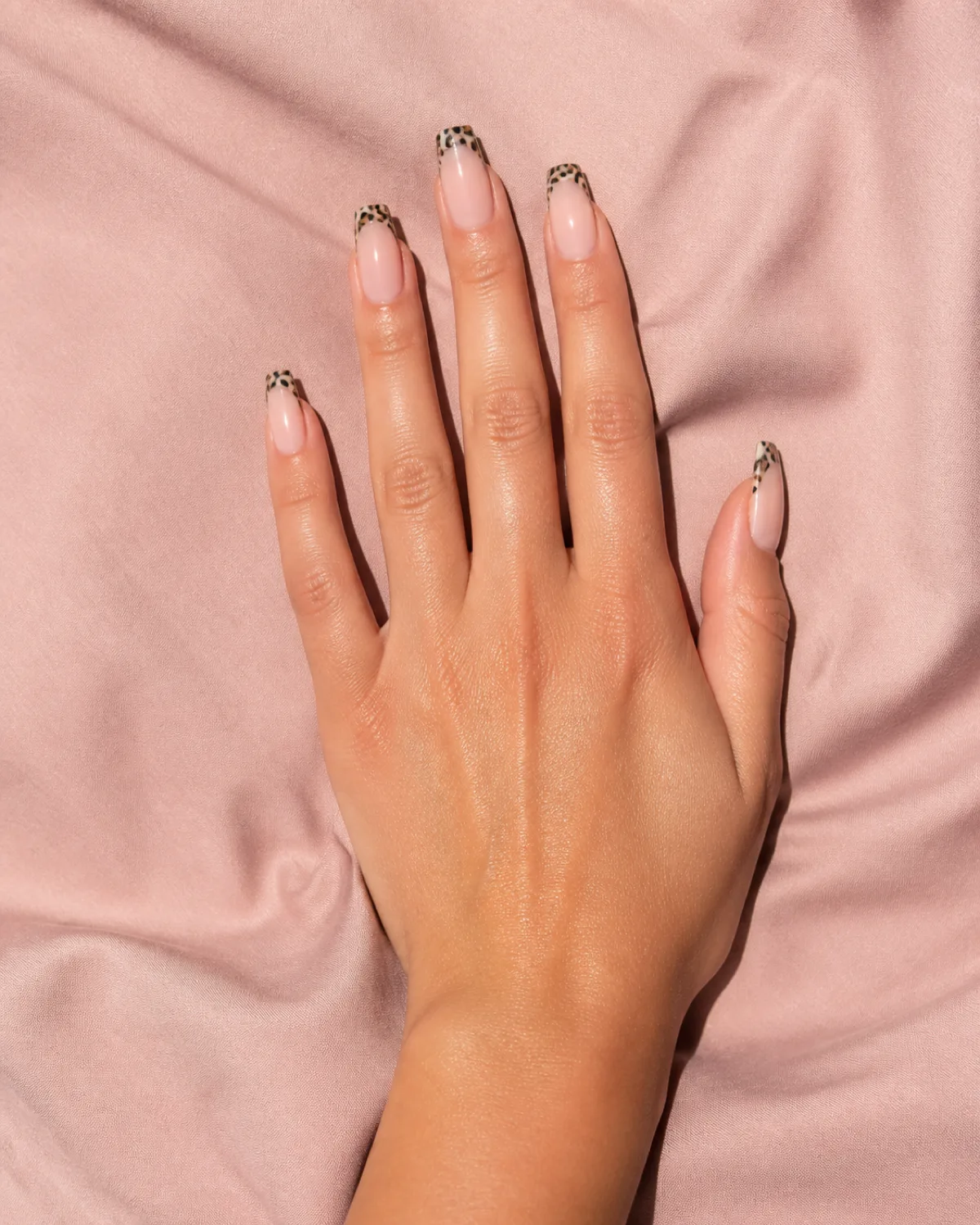 Single right hand with medium coffin nails showing leopard print French tips on nude base