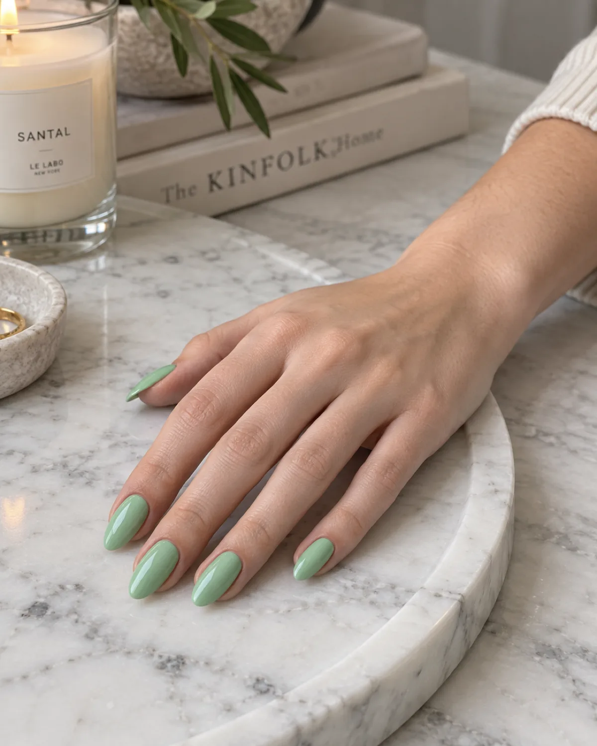 Solid mint green crème nails on almond shape resting on white marble tray