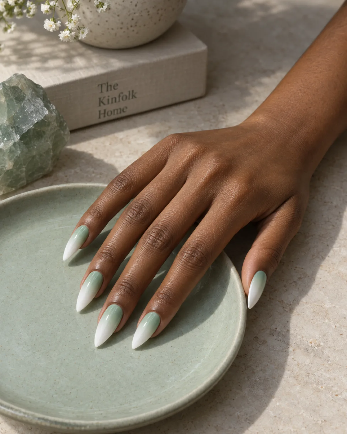 Mint green to white ombré fade nails on stiletto shape on pale sage ceramic dish