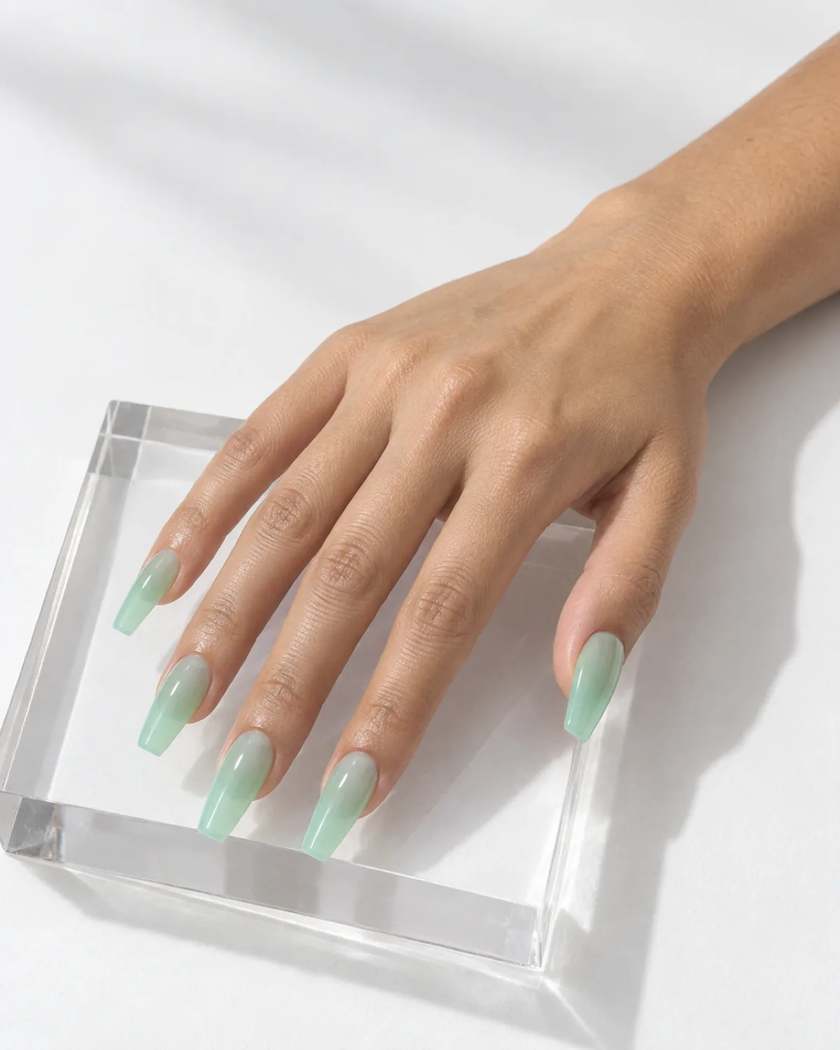Mint green jelly nails on coffin shape on clear acrylic riser with white background