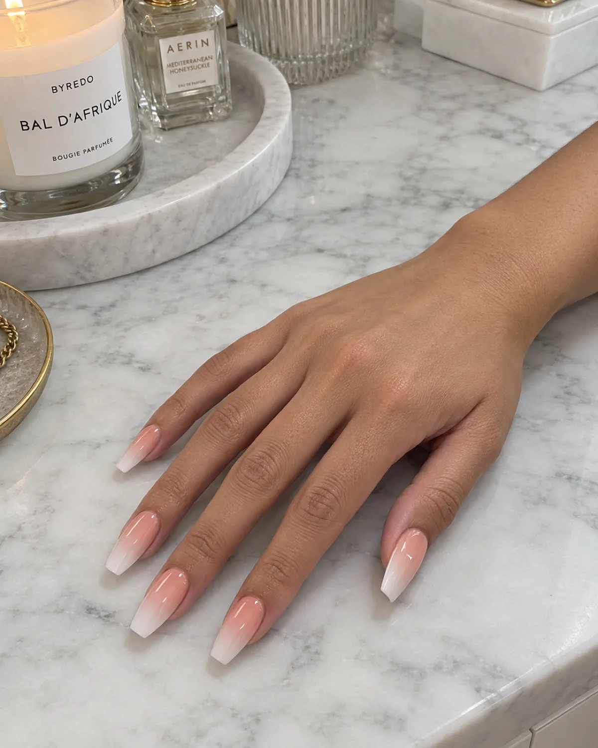 Single right hand with peach-to-white ombré coffin nails on a white marble surface
