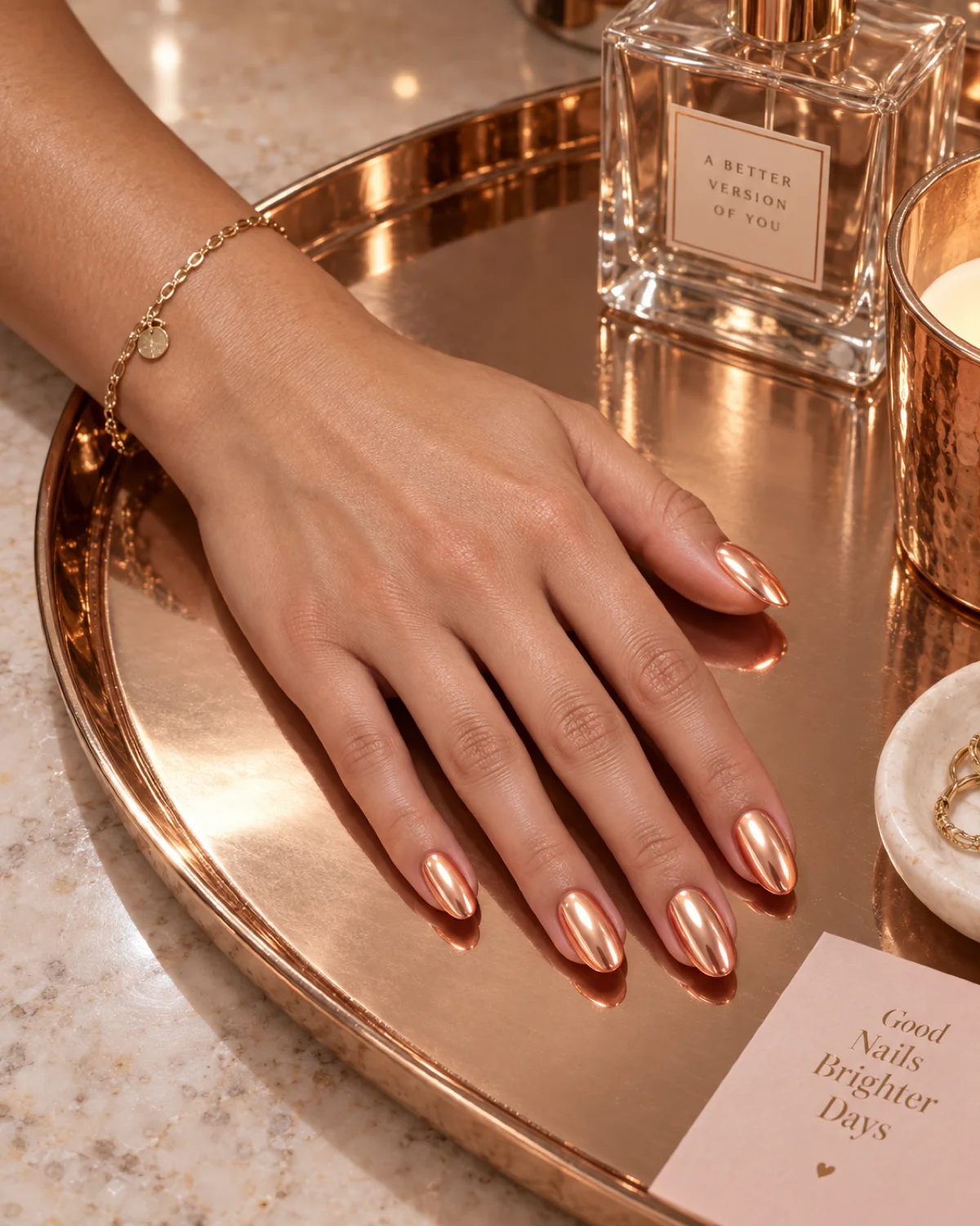 Single left hand with mirror-finish peach chrome oval nails on a rose-gold tray