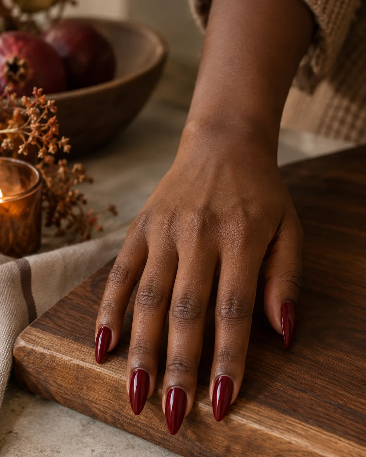 Deep cranberry red glossy stiletto nails on dark walnut cutting board